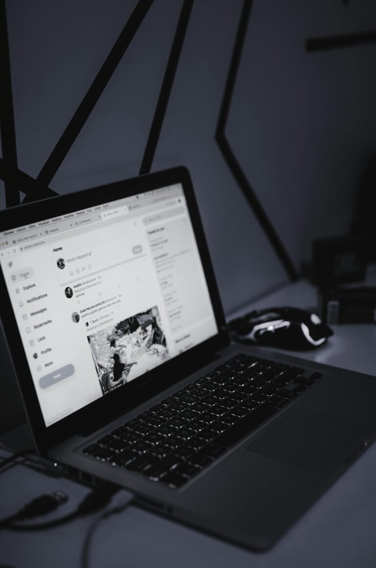 A sleek workspace featuring a laptop and a wireless mouse in a dimly lit room, fostering productivity.