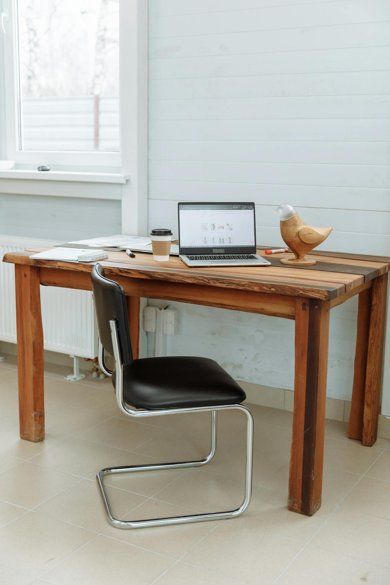 Simple office desk setup with a laptop, coffee cup, and wooden bird figurine.